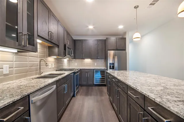 a large kitchen with stainless steel appliances granite countertop a sink stove and refrigerator