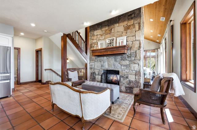 335 Bern Way Midway, UT 84049 - Photo 18 of 88 Great room featuring a prominent stone fireplace with a wood mantle, terracotta tile flooring, a wood-finish staircase, and a vaulted wood-paneled ceiling