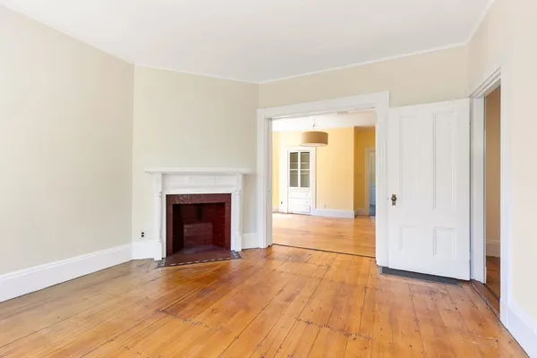 an empty room with wooden floor and fireplace