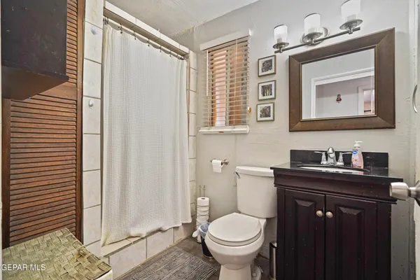 a bathroom with a granite countertop sink toilet and mirror