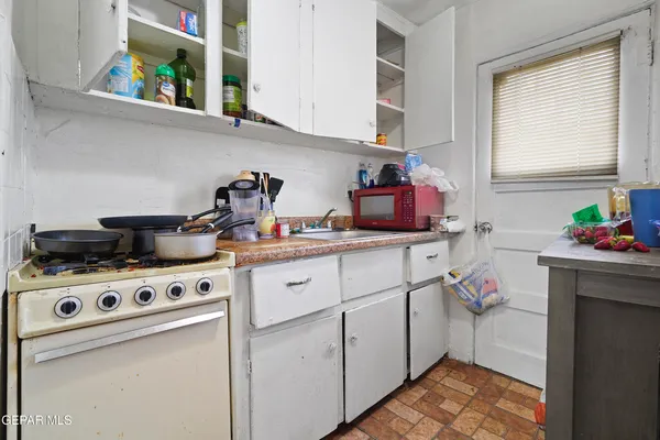 a kitchen with a stove and a white wooden cabinets