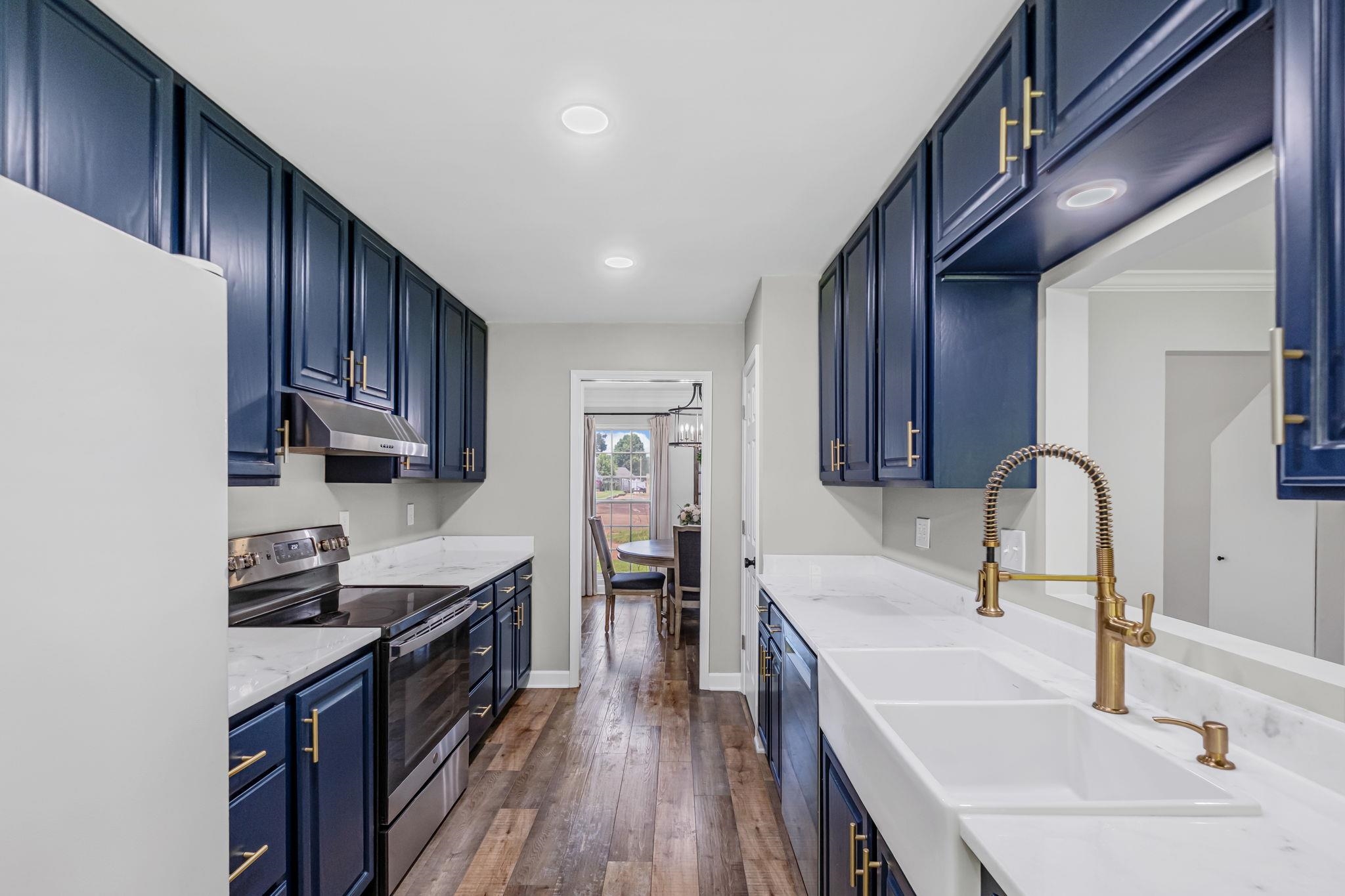 4729 Cedar Ridge Drive Millington, TN 38053 - Photo 14 of 40 Galley kitchen featuring navy cabinetry with gold-tone hardware, white countertops, stainless steel appliances, and wood-finish flooring