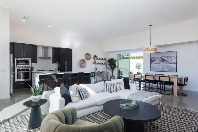a living room with furniture kitchen view and a chandelier