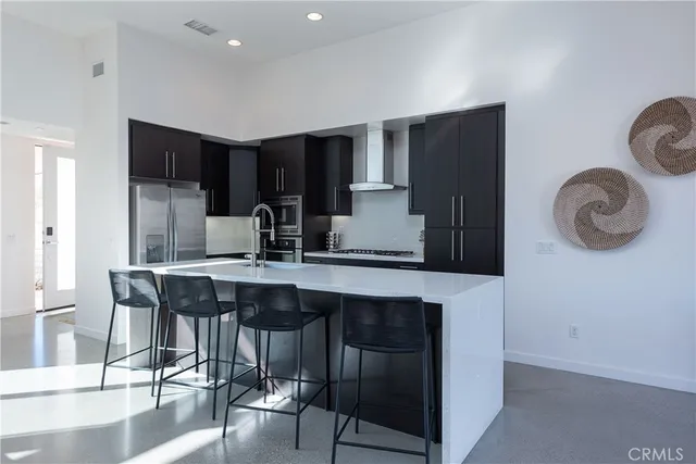 a kitchen with stainless steel appliances granite countertop a table chairs refrigerator and sink