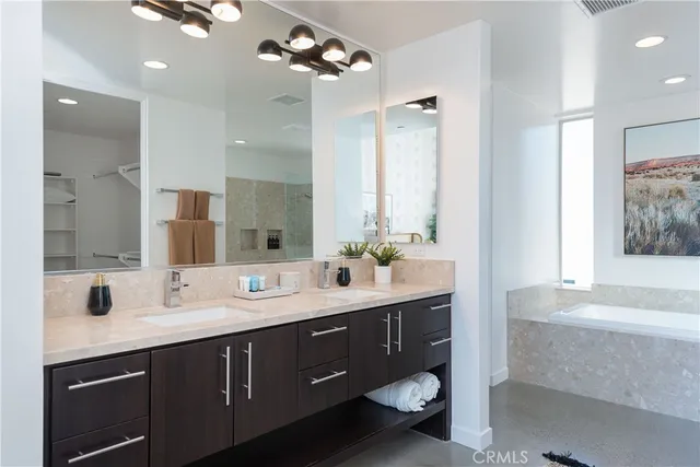 a bathroom with a double vanity sink mirror and bathtub