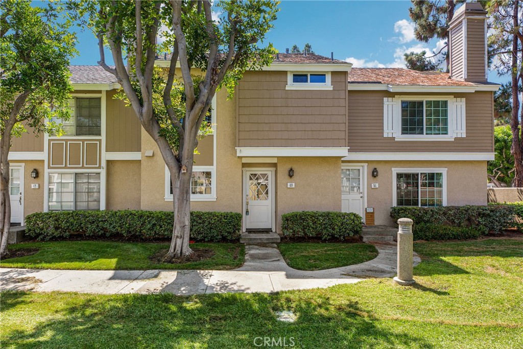 49 Thicket, Unit 36 Irvine, CA 92614 - Photo 2 of 2 a front view of a house with a yard and garage
