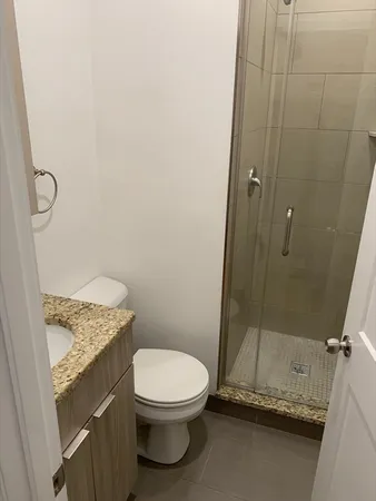 a bathroom with a granite countertop toilet and a sink
