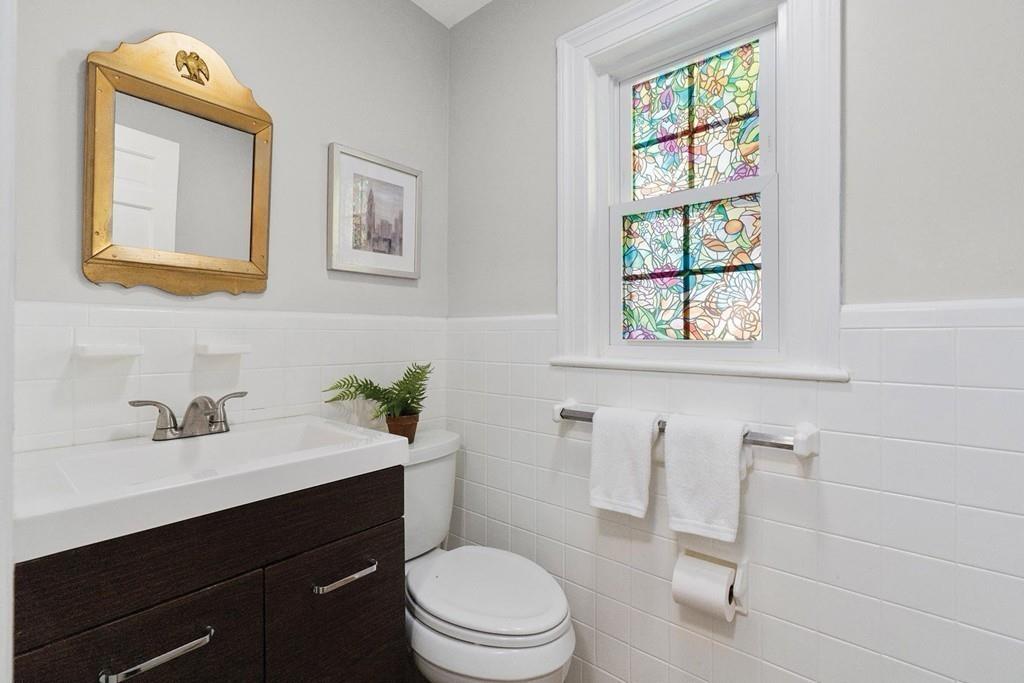 118 Wallis Road Brookline, MA 02467 - Photo 23 of 29 a bathroom with a toilet a sink a mirror and window