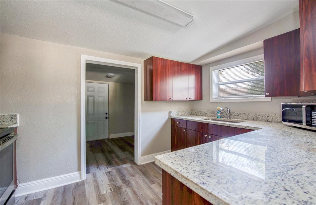 1516 East Waters Avenue Tampa, FL 33604 - Photo 12 of 25 a kitchen with granite countertop wooden cabinets and white appliances
