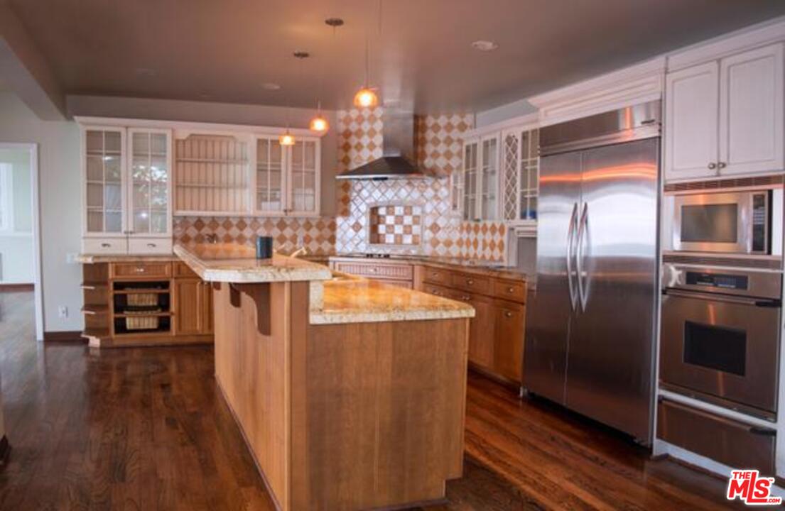 18125 Coastline Drive, Unit A Malibu, CA 90265 - Photo 5 of 9 a kitchen with stainless steel appliances granite countertop a refrigerator a stove and a wooden floors