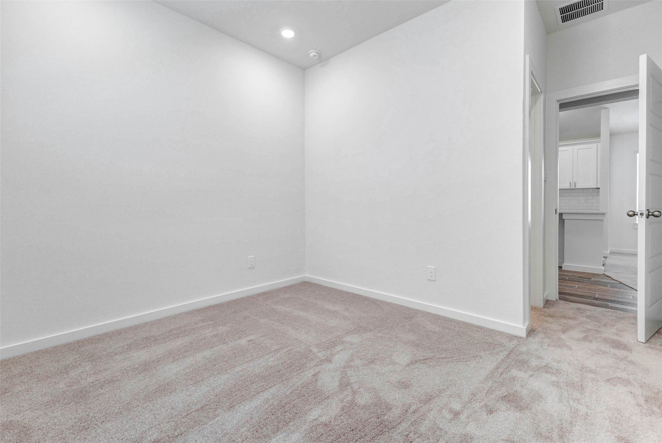6475 Escondido Drive Rosharon, TX 77583 - Photo 22 of 32 This secondary bedroom offers soft carpet, tall ceilings, recessed lighting, and a simple neutral design that can easily work as a guest room, office, nursery, or flex space. The nearby doorway provides convenient access back toward the main living areas and kitchen.