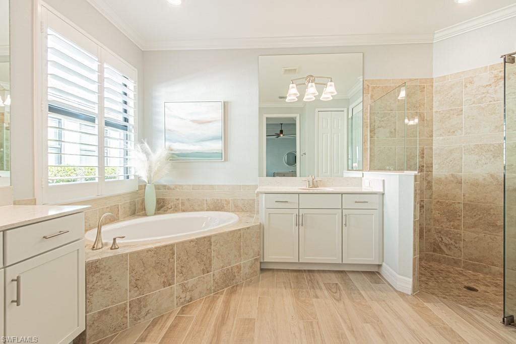 1869 Mustique Street Naples, FL 34120 - Photo 21 of 48 a spacious bathroom with a double vanity sink a large mirror and a bathtub