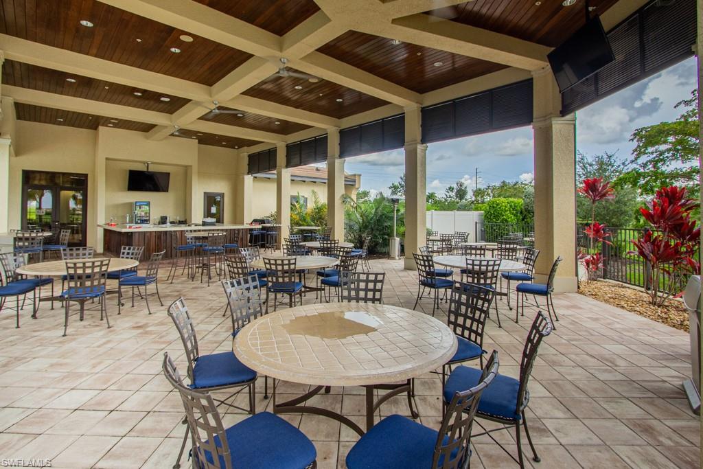 1869 Mustique Street Naples, FL 34120 - Photo 36 of 48 a view of a patio with table and chairs potted plants and floor to ceiling window