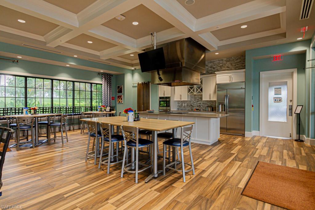 1869 Mustique Street Naples, FL 34120 - Photo 40 of 48 a dining hall with stainless steel appliances granite countertop a stove a refrigerator a kitchen island a dining table and chairs with wooden floor