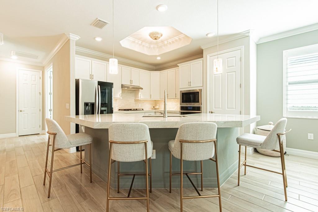 1869 Mustique Street Naples, FL 34120 - Photo 9 of 48 a kitchen with stainless steel appliances kitchen island granite countertop a dining table chairs and a refrigerator