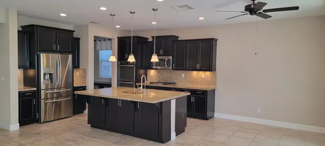a kitchen with stainless steel appliances granite countertop a sink and a refrigerator