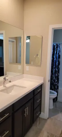 a white toilet sitting next to a white sink and vanity