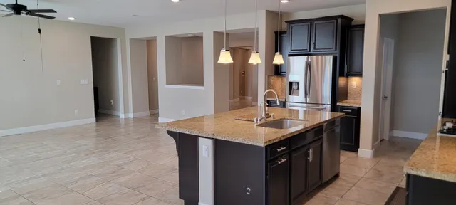 a kitchen with kitchen island granite countertop a refrigerator and a stove