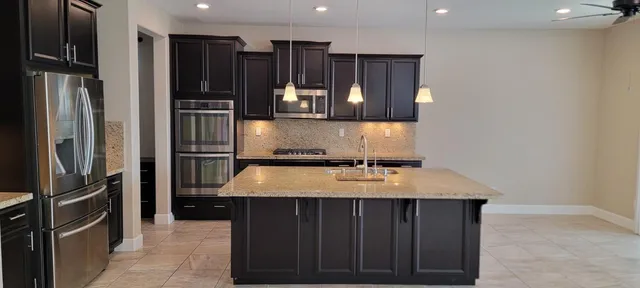 a kitchen with kitchen island a counter top space cabinets and stainless steel appliances