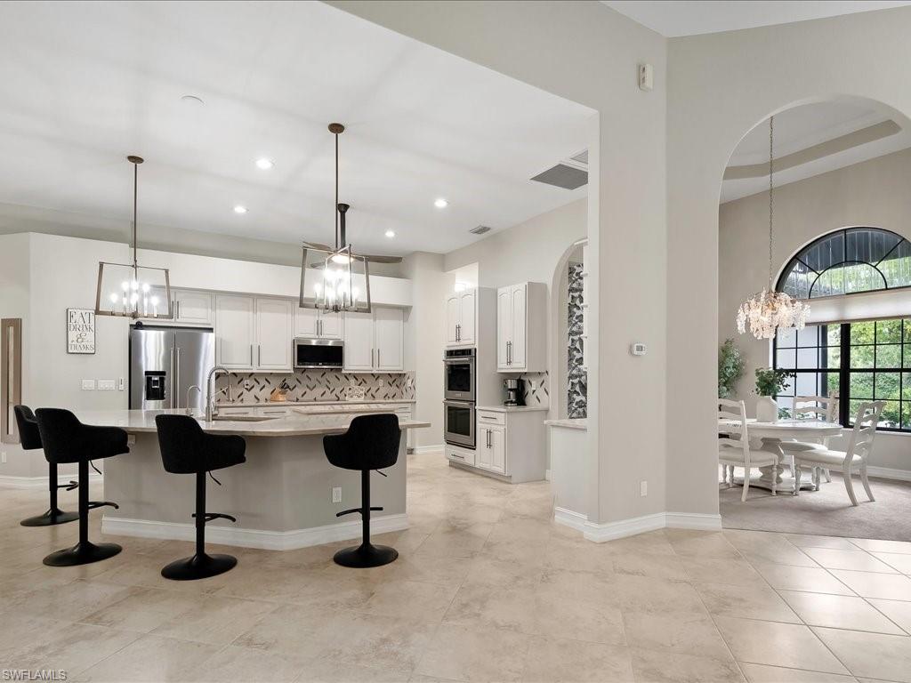2360 19th Street Southwest Naples, FL 34117 - Photo 18 of 50 Kitchen with appliances with stainless steel finishes, a chandelier, a kitchen bar, light countertops, and tasteful backsplash