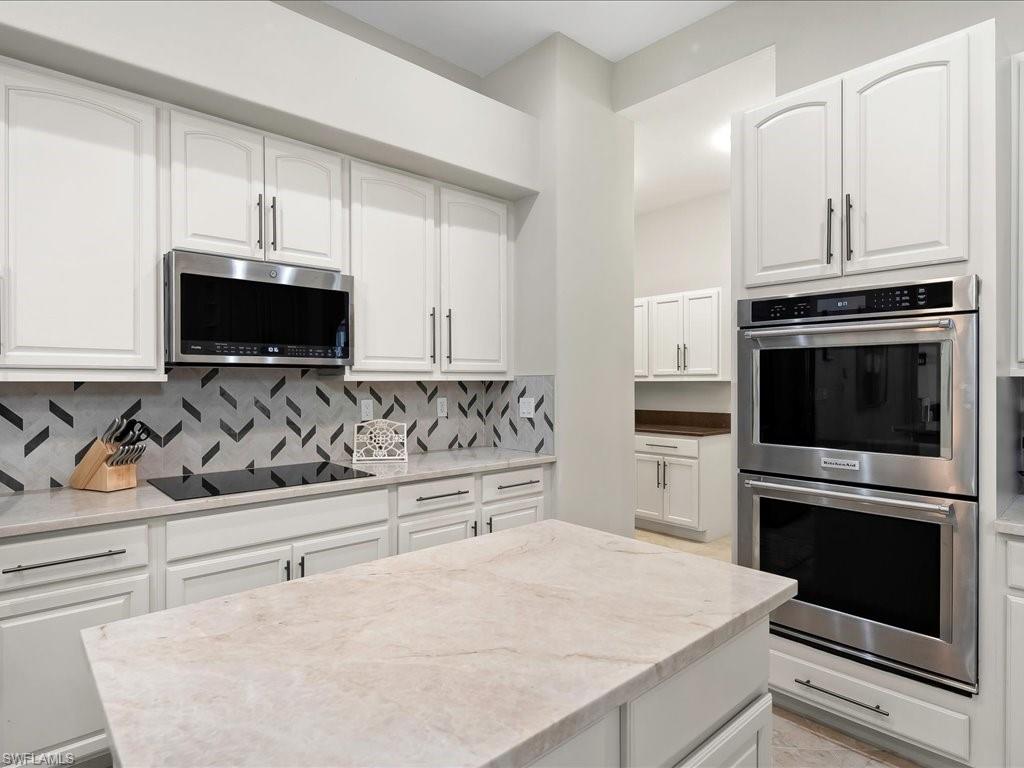 2360 19th Street Southwest Naples, FL 34117 - Photo 20 of 50 Kitchen featuring appliances with stainless steel finishes, decorative backsplash, white cabinets, and light stone counters