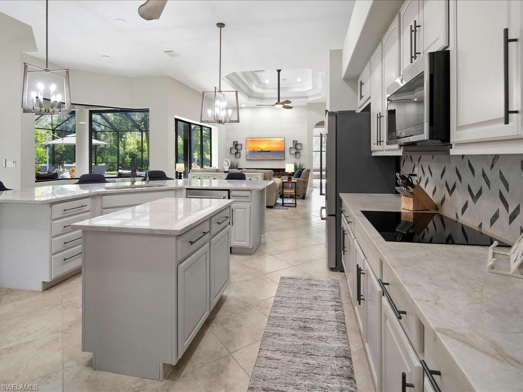 2360 19th Street Southwest Naples, FL 34117 - Photo 21 of 50 Kitchen with a chandelier, appliances with stainless steel finishes, a spacious island, a sink, and decorative backsplash