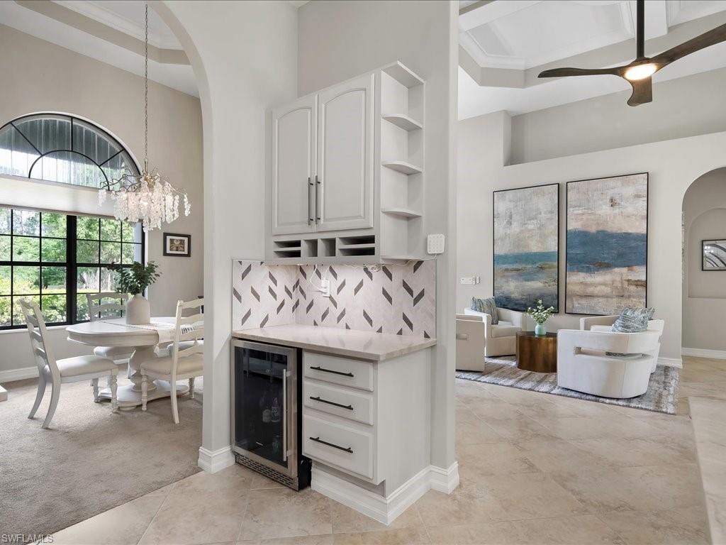 2360 19th Street Southwest Naples, FL 34117 - Photo 22 of 50 Indoor dry bar with wine cooler, arched walkways, a high ceiling, a chandelier, and tasteful backsplash