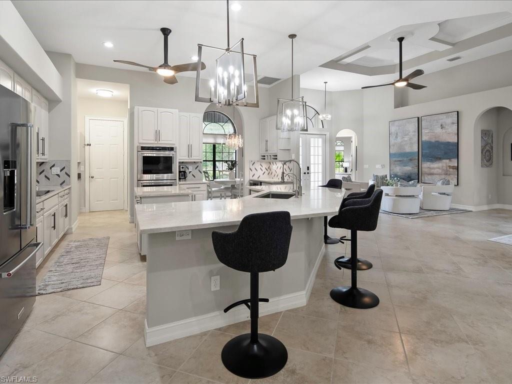 2360 19th Street Southwest Naples, FL 34117 - Photo 23 of 50 Kitchen with a ceiling fan, a sink, appliances with stainless steel finishes, a large island, and a high ceiling