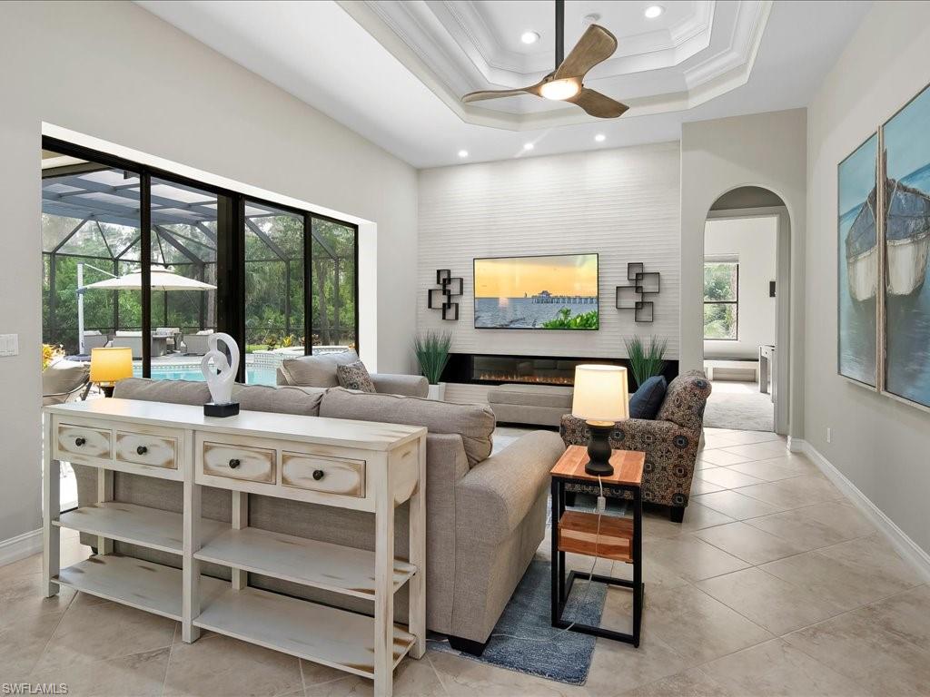 2360 19th Street Southwest Naples, FL 34117 - Photo 24 of 50 Tiled living room featuring ceiling fan, arched walkways, ornamental molding, a tray ceiling, and recessed lighting