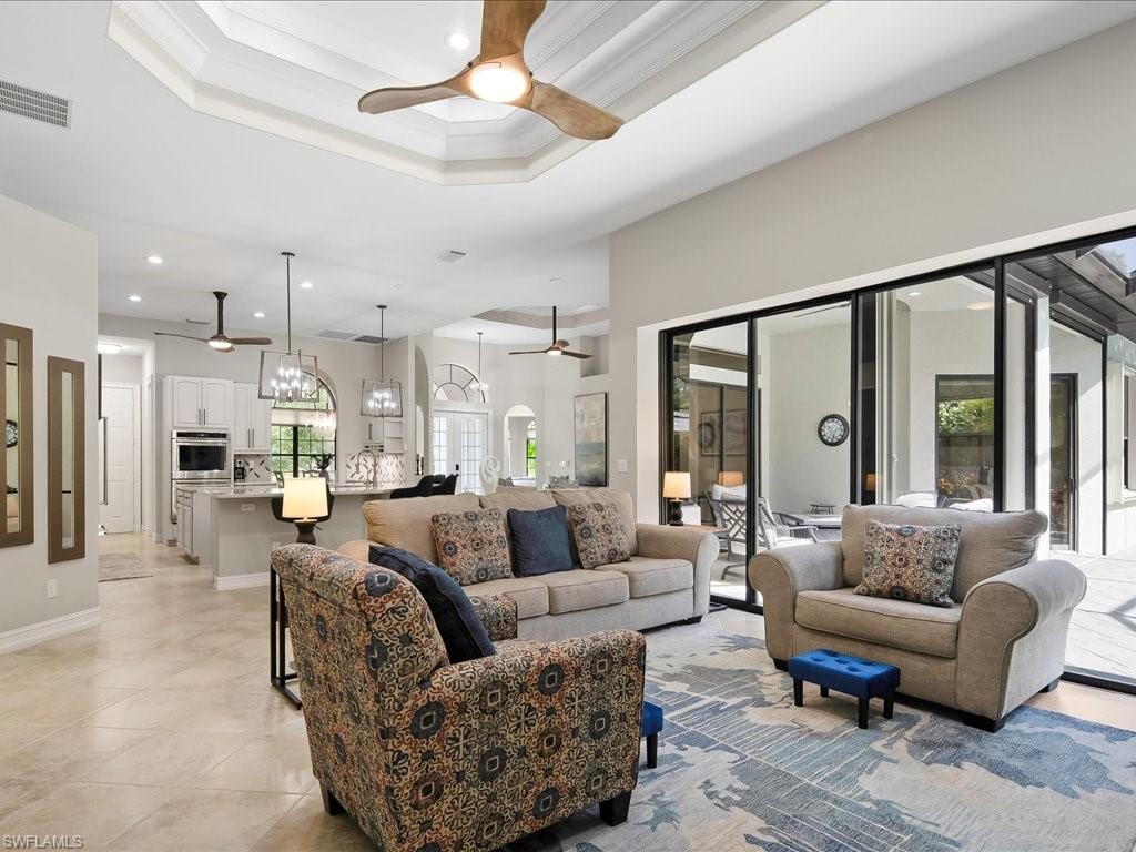 2360 19th Street Southwest Naples, FL 34117 - Photo 25 of 50 Living room with ceiling fan, recessed lighting, light tile patterned floors, a chandelier, and crown molding