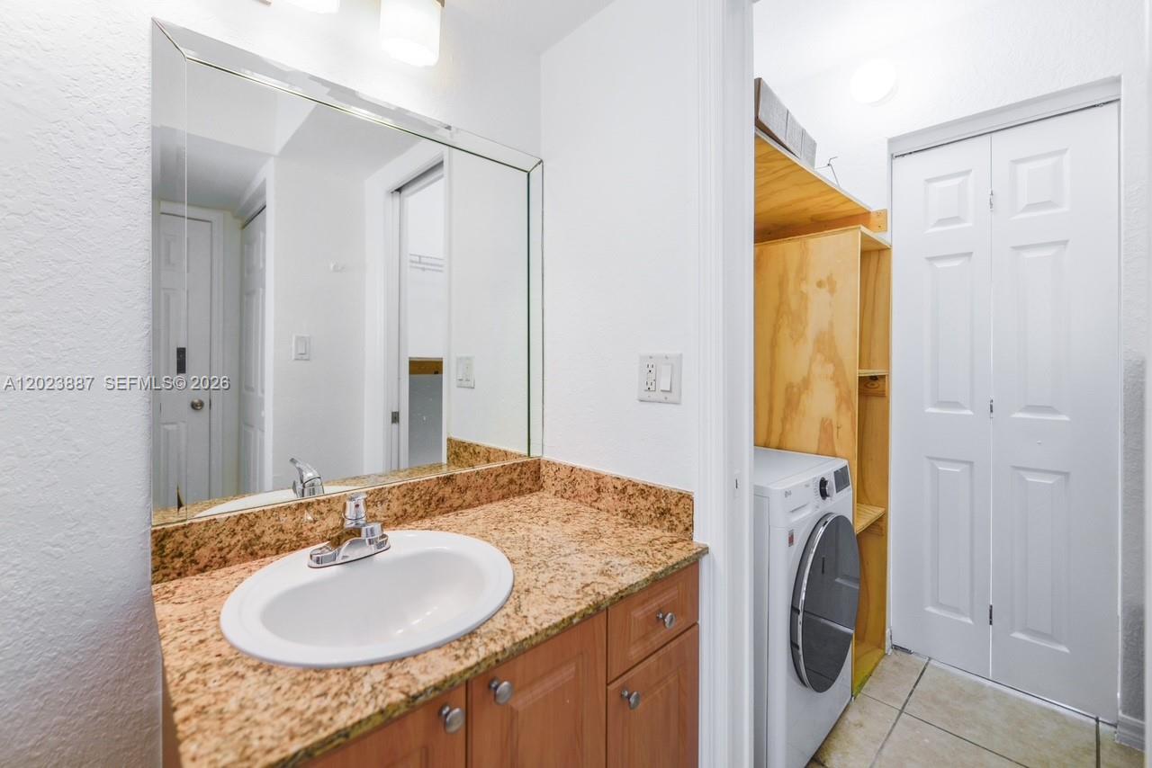 7737 Southwest 88th Street, Unit C312 Miami, FL 33156 - Photo 24 of 32 a bathroom with a granite countertop sink and a mirror