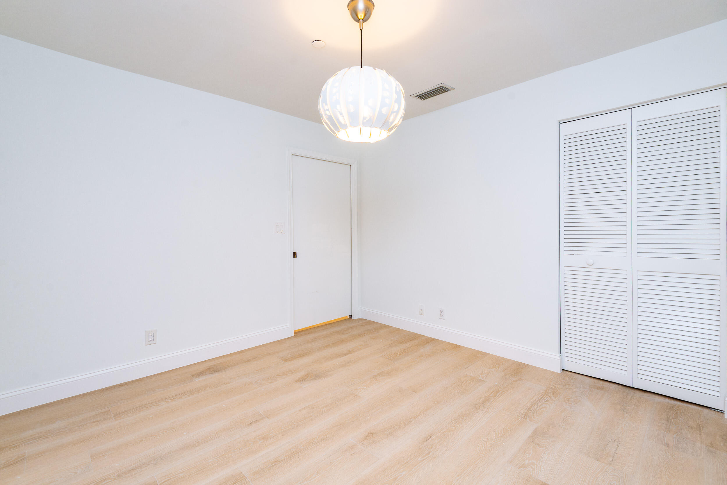 380 Northwest 67th Street, Unit J204 Boca Raton, FL 33487 - Photo 21 of 43 a view of a room with wooden floor and chandelier