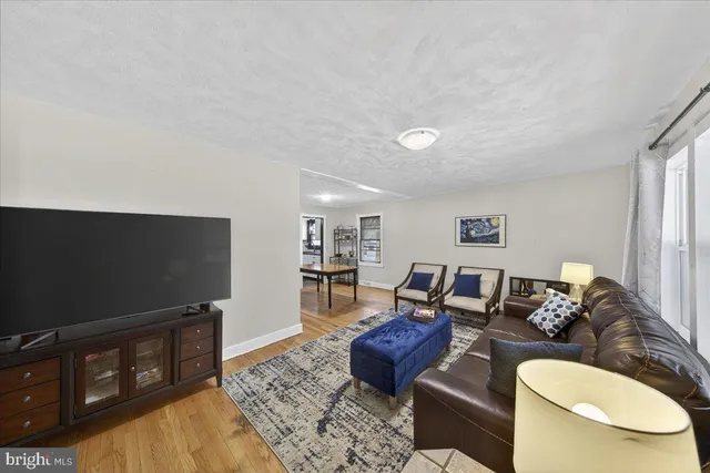 a view of a hallway with wooden floor and a bathroom