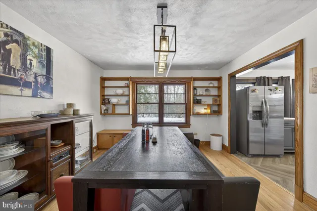 a dining room with wooden floor a chandelier a wooden table and chairs
