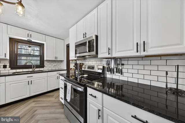 a kitchen with stainless steel appliances granite countertop a stove a sink and a white cabinets