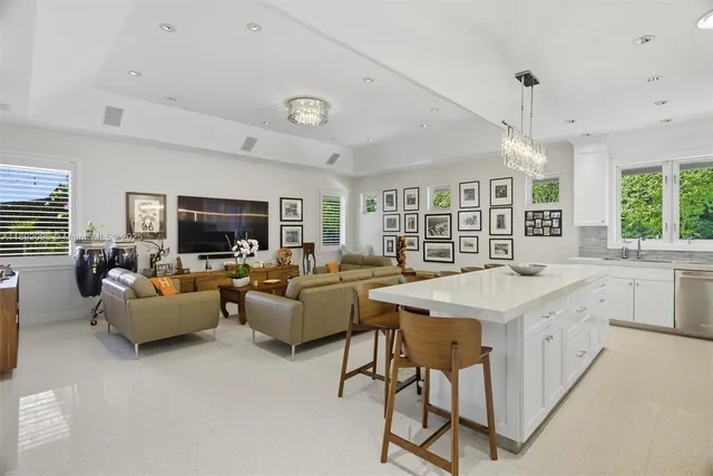 a living room with furniture kitchen view and a large window