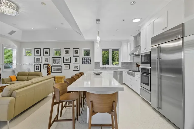 a kitchen with stainless steel appliances granite countertop a dining table chairs and a refrigerator
