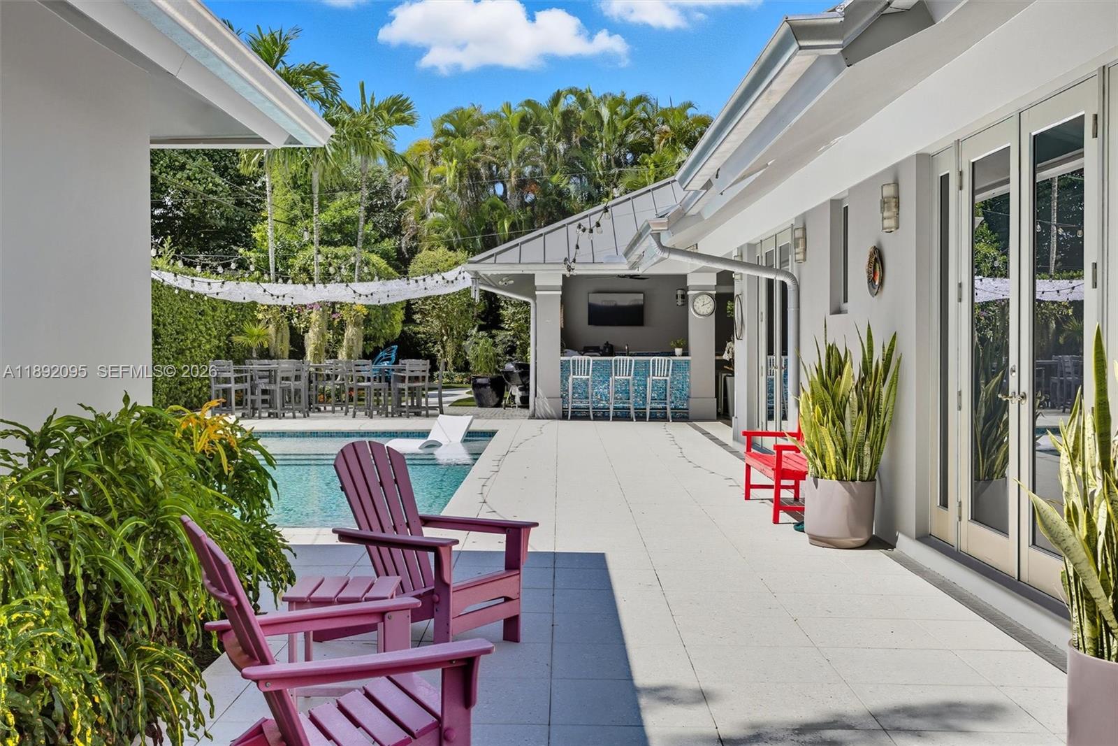 5800 Southwest 99th Terrace Pinecrest, FL 33156 - Photo 48 of 62 a view of a patio with table and chairs potted plants and floor to ceiling window
