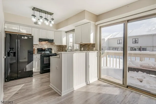 a kitchen with stainless steel appliances granite countertop a refrigerator a sink a stove and white cabinets