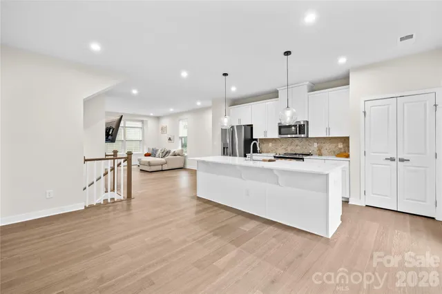 a kitchen with stainless steel appliances kitchen island hard wood floors and white cabinets