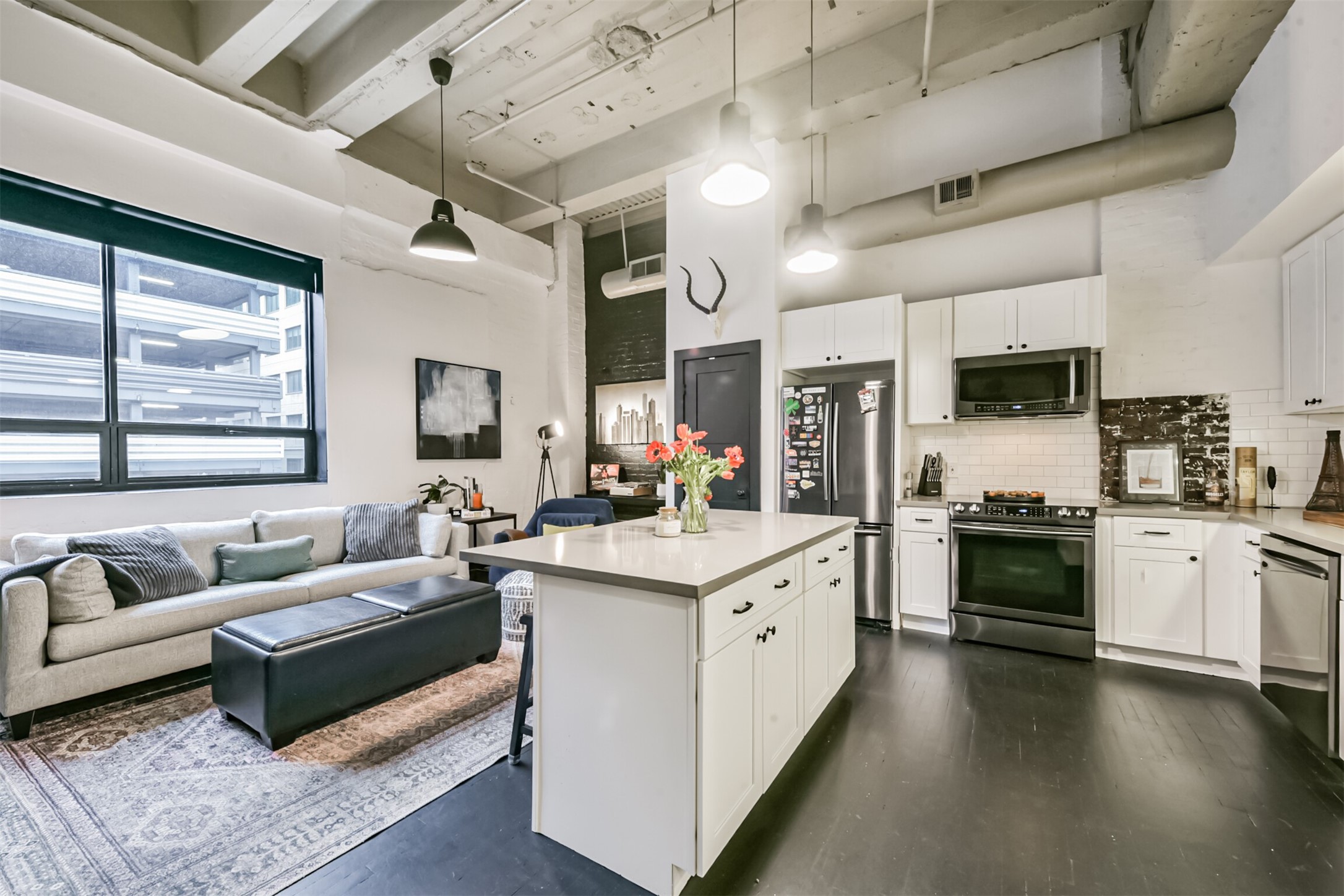 705 Main Street, Unit 321 Houston, TX 77002 - Photo 21 of 39 a large white open kitchen with stainless steel appliances kitchen island granite countertop a lot of white cabinets with wooden floors