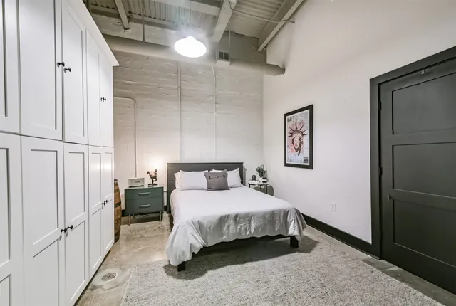 a spacious bedroom with a bed a table and painting on the wall