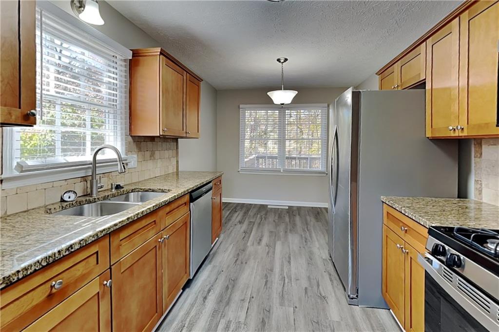 3094 Calumet Circle Northwest Kennesaw, GA 30152 - Photo 4 of 23 a kitchen with granite countertop a sink cabinets wooden floor and stainless steel appliances