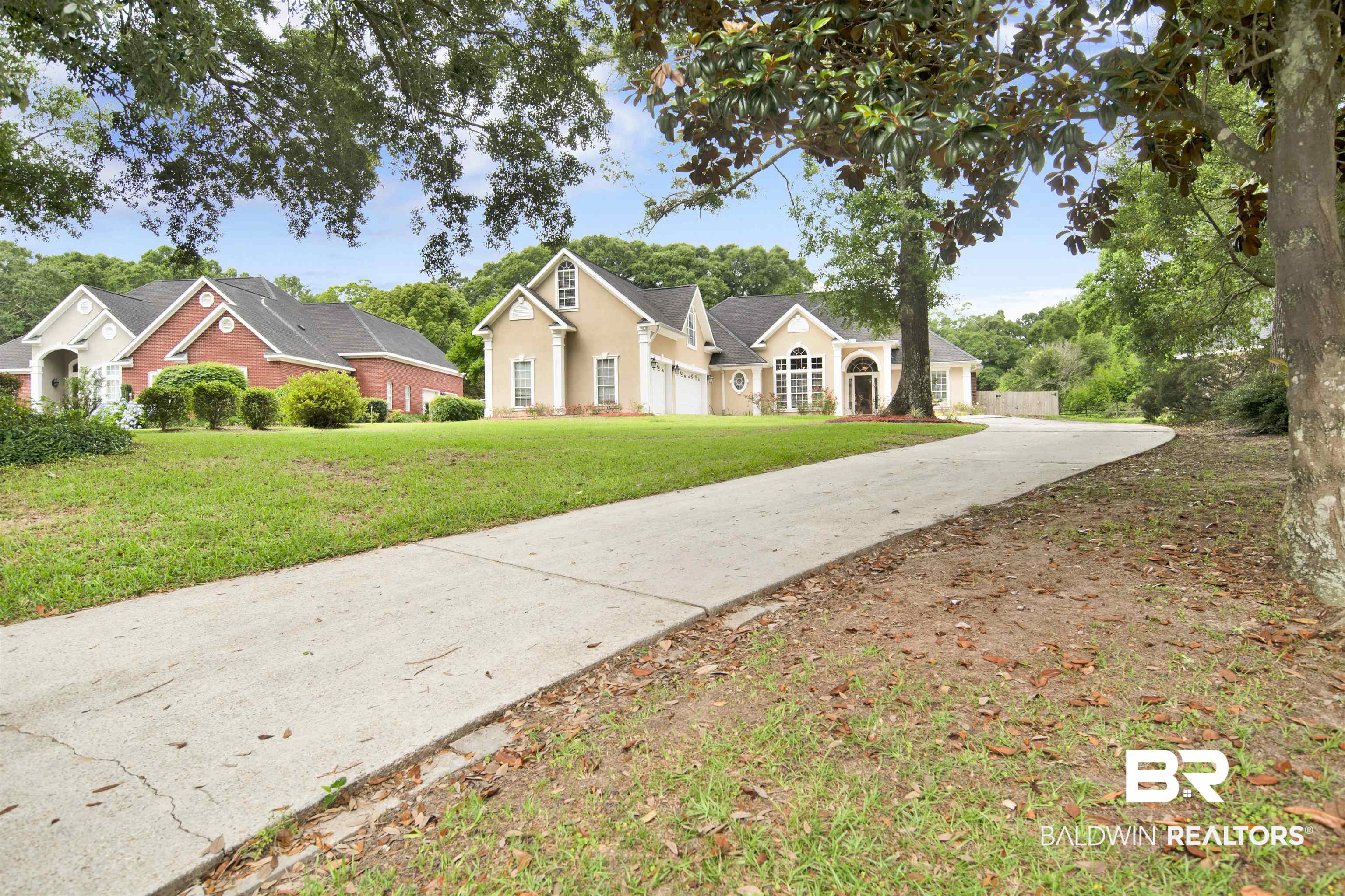 8847 Dawes Lake Road South Mobile, AL 36619 - Photo 2 of 47 Spacious concrete driveway leading to a residence featuring a tan stucco exterior, multiple gables, and a two-car garage