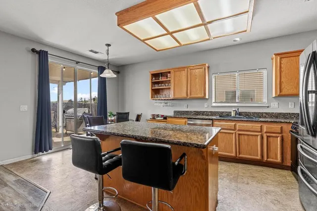 a kitchen with granite countertop kitchen island stainless steel appliances a sink stove and cabinets