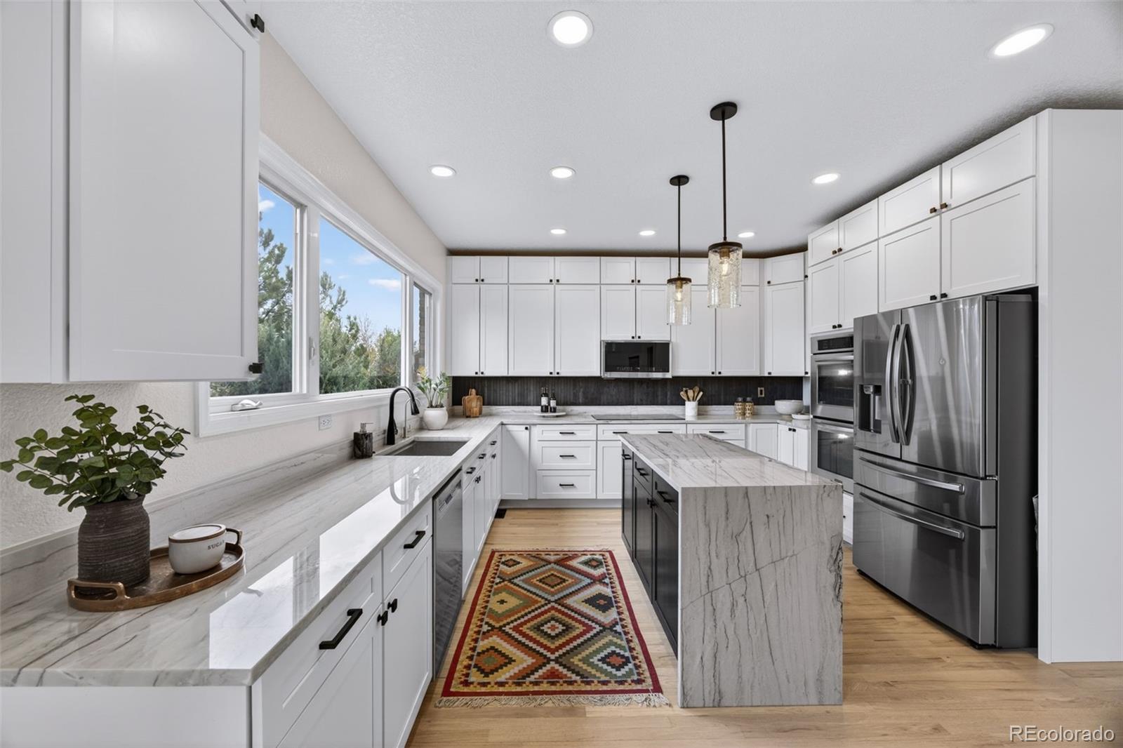 551 Seth Place Castle Pines, CO 80108 - Photo 11 of 50 a kitchen with kitchen island granite countertop a sink stainless steel appliances and cabinets