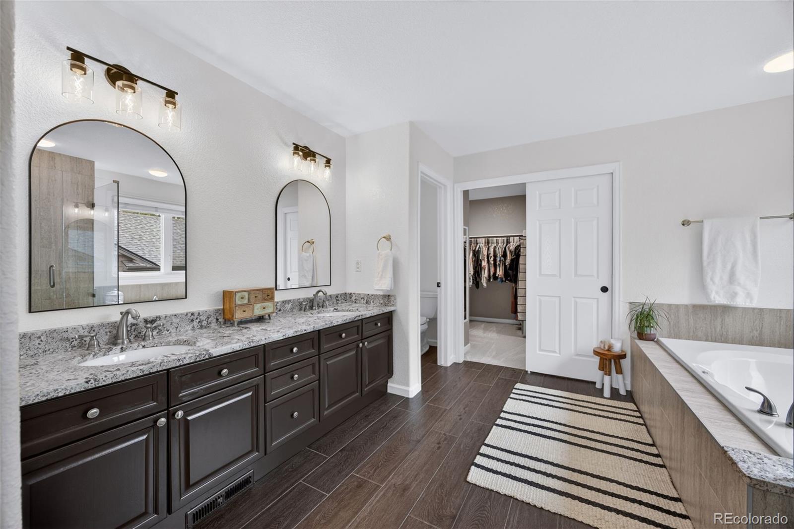 551 Seth Place Castle Pines, CO 80108 - Photo 25 of 50 a spacious bathroom with a granite countertop sink mirror and bathtub