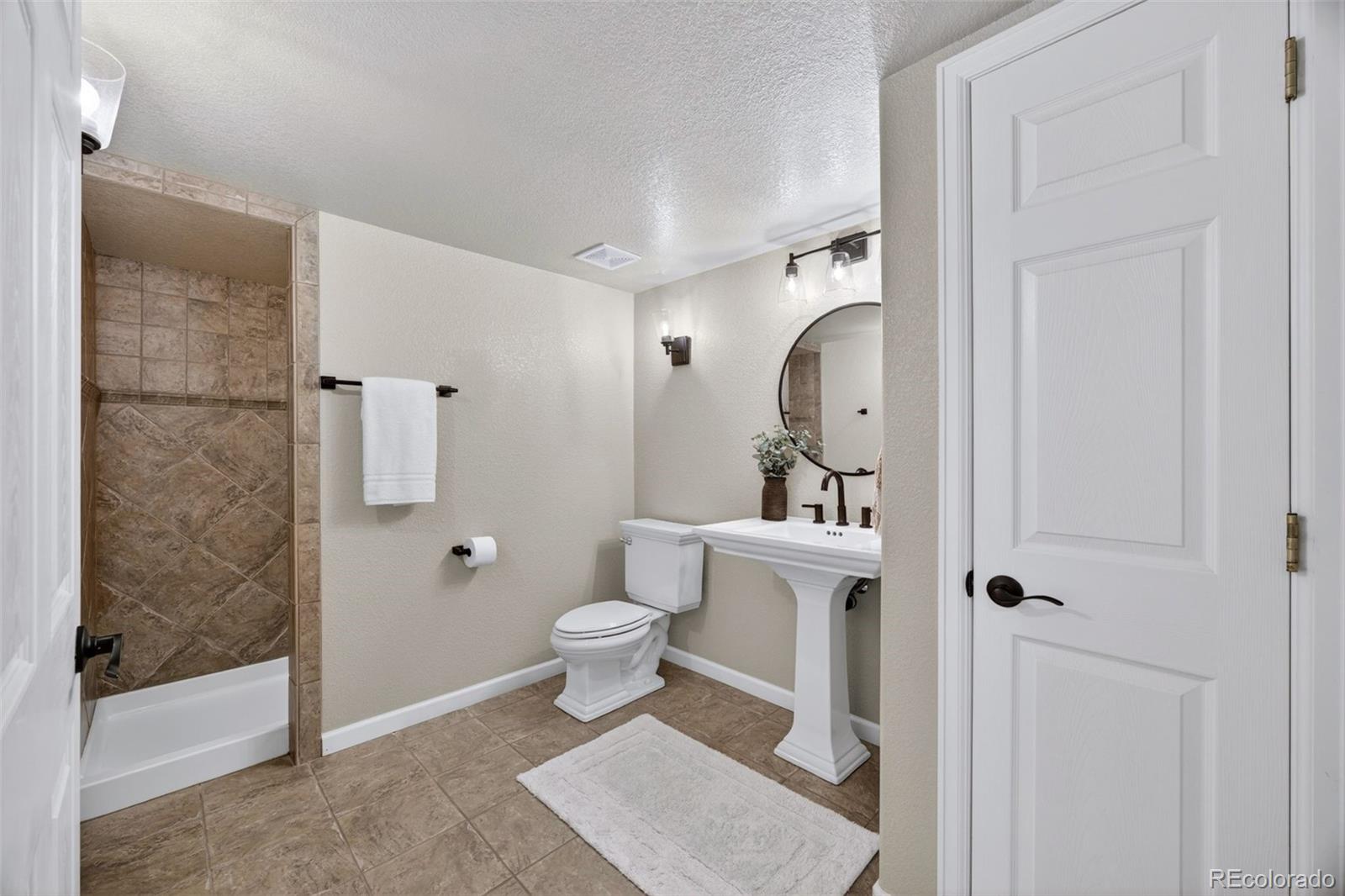 551 Seth Place Castle Pines, CO 80108 - Photo 37 of 50 a bathroom with a toilet a sink and shower