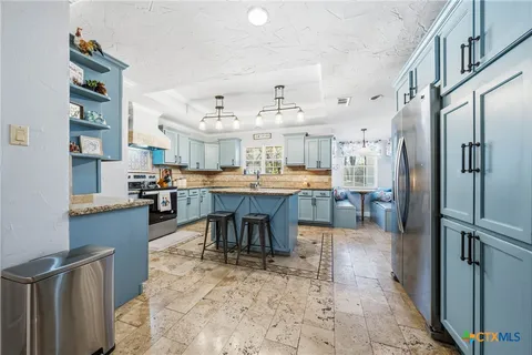 a kitchen with stainless steel appliances kitchen island granite countertop a refrigerator and a stove