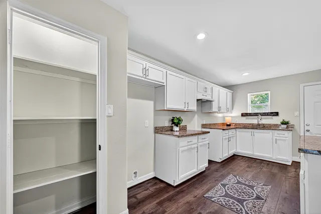 a kitchen with white cabinets and sink